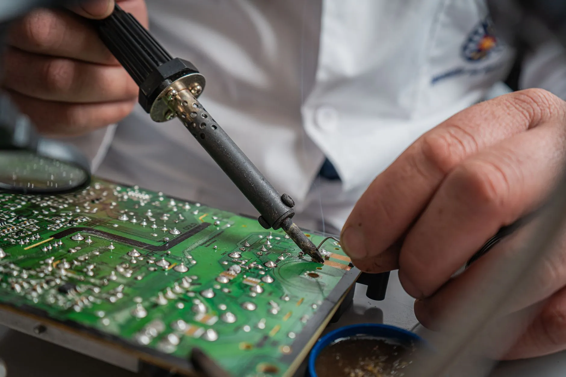 Technician performing precise soldering on a circuit board for electronics repair.